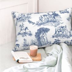 a blue and white pillow sitting on top of a bed next to an open book