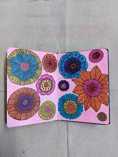 an open notebook decorated with colorful flowers on a gray surface, showing the inside pages