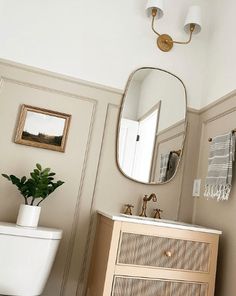 a white toilet sitting next to a wooden cabinet in a bathroom under a large mirror