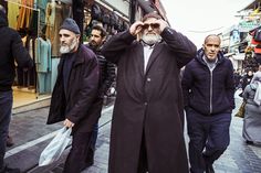 a group of men walking down a street next to each other with bags on their heads