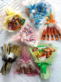 various candy wrapped in cellophane and tied with ribbons on a bed sheet,