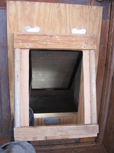 an open window in the side of a wooden wall with no glass on it, and someone's feet standing next to it