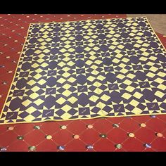 a large black and yellow rug on top of a red floor with small white dots