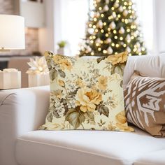 a living room with a christmas tree in the background and flowers on the pillow cover