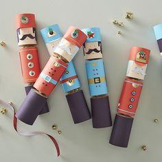 four rolls of toilet paper decorated like nutcrackers with ribbons and confetti sprinkles