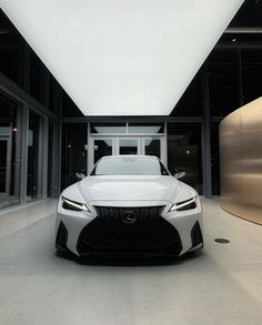 a white sports car parked in front of a building with glass walls and doors on both sides