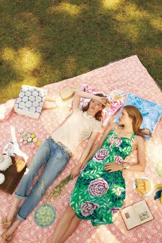 two women laying on a blanket in the grass