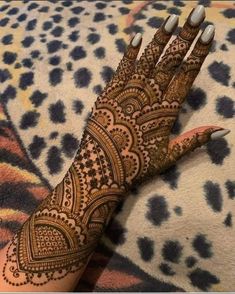 henna tattoo on someone's hand that is showing the intricate pattern and colors