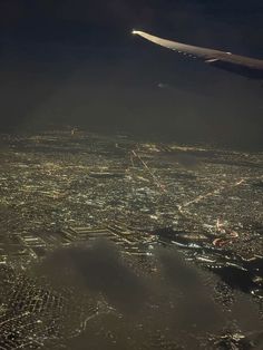 an airplane wing flying over a city at night