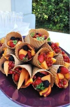 a purple plate topped with cones filled with fruit