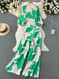 a green and white jumpsuit sitting on top of a rug next to a hat