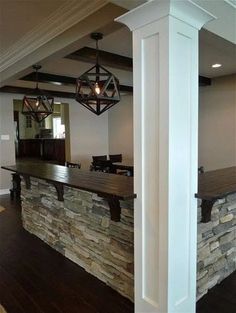 a bar in the middle of a room with wood floors and white columns on either side