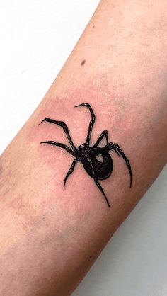 a black spider tattoo on the arm