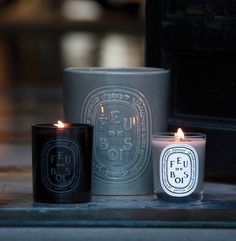 two candles sitting next to each other on the ground in front of a black box