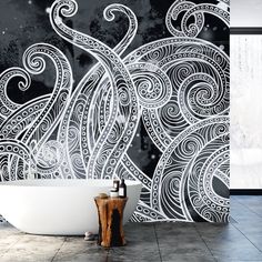 a bath tub sitting next to a wall with an artistic design on the wall behind it