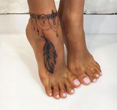 a woman's foot with a tattoo on it and a feather hanging from the ankle