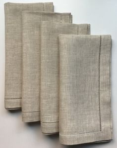 four linen napkins are lined up on a white surface