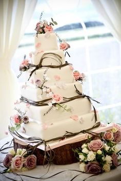 a three tiered wedding cake sitting on top of a table next to a window