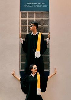 two people dressed in black and yellow standing next to each other near a building window