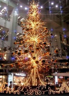 a lighted christmas tree in the middle of a shopping mall with lots of lights on it