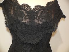 Gorgeous vintage black alencon lace blouse for evening wear. It is labeled Watters and Watters with the fabric contents and care pictured. My guess is 60's - 80's . This lace is fabulous with heavy cording around the flowers in an all over floral pattern. The top has slight off the shoulder wide straps or sleeves which fall to a v shape on both front and back. It is fitted along the waist. All edges have the eyelash of the lace showing on the scalloped edging. Inside is lined in both a netting a Elegant Fitted Lace For Formal Occasions, Elegant Fitted Lace For Evening, Elegant Fitted Evening Lace, Black Scalloped Lace Top For Night Out, Black Lace Top With Lace Trim For Formal Events, Black Lace Top With Lace Trim For Formal Occasions, Formal Black Lace Top With Lace Trim, Black Lace Top For Formal Occasions, Fitted Lace Bodice For Evening