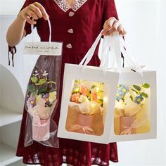 a woman holding two bags with flowers in them