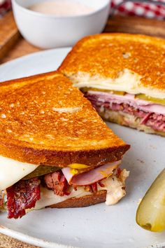 a sandwich cut in half on a plate next to a pickle