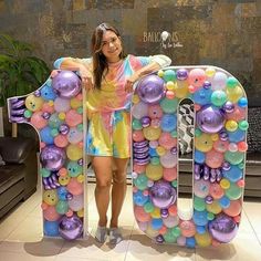 a woman standing next to a giant balloon letter