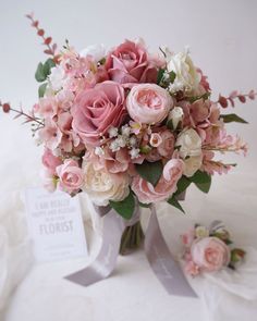 a bouquet of pink and white flowers sitting on top of a table