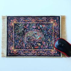 a computer mouse sitting on top of a rug next to a black and red mouse pad