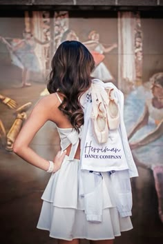 a woman is standing in front of a wall with ballet shoes on it and her back to the camera