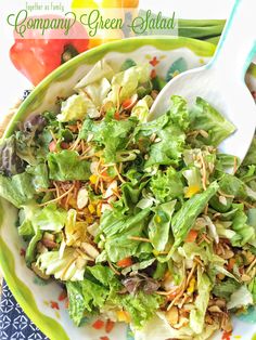 a salad with lettuce, carrots and other vegetables in a green bowl