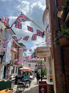 the british flags are flying in the air above tables and chairs on the side walk