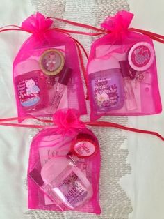 three pink bags filled with personal care items on top of a white tablecloth covered surface