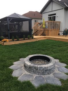 a fire pit sitting in the middle of a lush green field next to a house