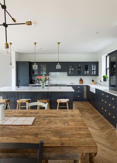 a kitchen with wooden table and chairs next to an island in the middle of it