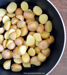 potatoes are being cooked in a frying pan on a wooden table, top view