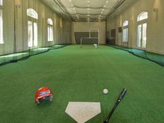 an indoor batting cage with a baseball bat and glove on the ground