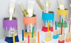 some toothbrushes are sitting in tins on a table with colorful paint brushes