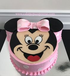 a minnie mouse cake with pink icing and white polka dots on it's face