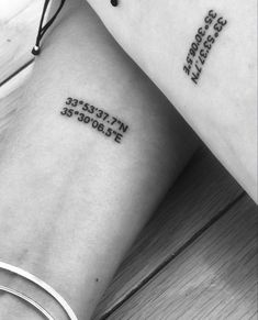 two small tattoos on the arms with words written in different languages and numbers tattooed on them