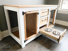 a wooden dog house with two bowls on the bottom and one drawer open to allow food