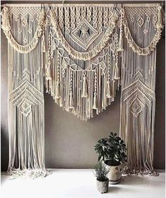 a potted plant sitting on top of a table next to macrame curtains