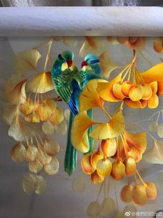 two birds sitting on top of yellow flowers in a glass container with leaves and berries