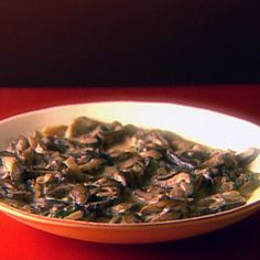 a white bowl filled with mushrooms on top of a red table