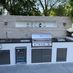 an outdoor kitchen with built in grill and sink