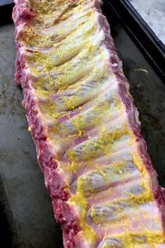 raw meat being cooked in an oven with yellow and red sauce on it's side