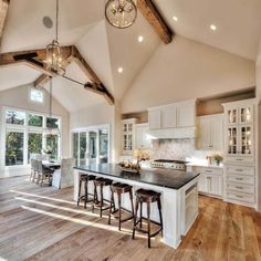 a large kitchen with white cabinets and wooden floors