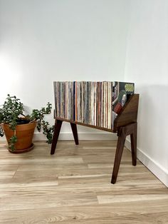 an old record player sitting on top of a wooden stand next to a potted plant