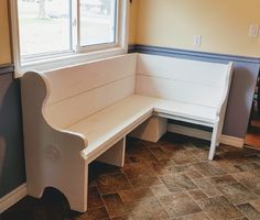 a white bench sitting in front of a window next to a tiled floor and wall